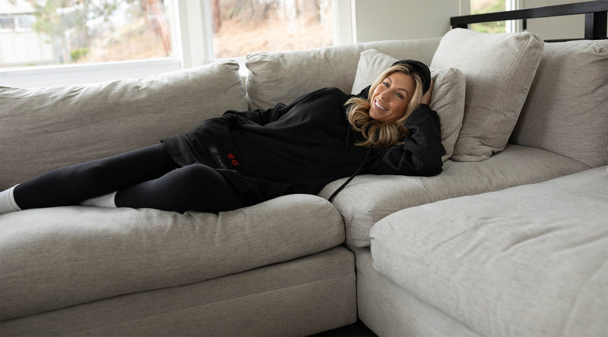 Woman resting on a sofa in the TherapyWear Relief Hoodie