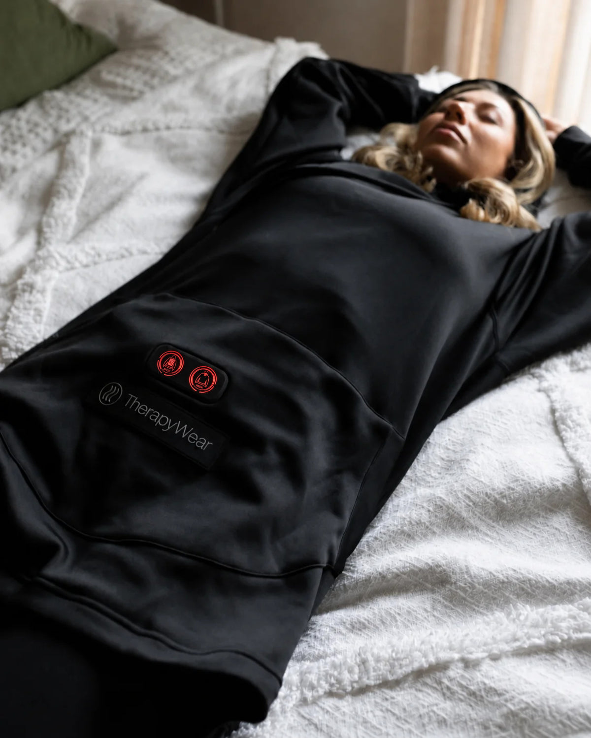 Woman relaxing on a bed in the TherapyWear Relief Hoodie