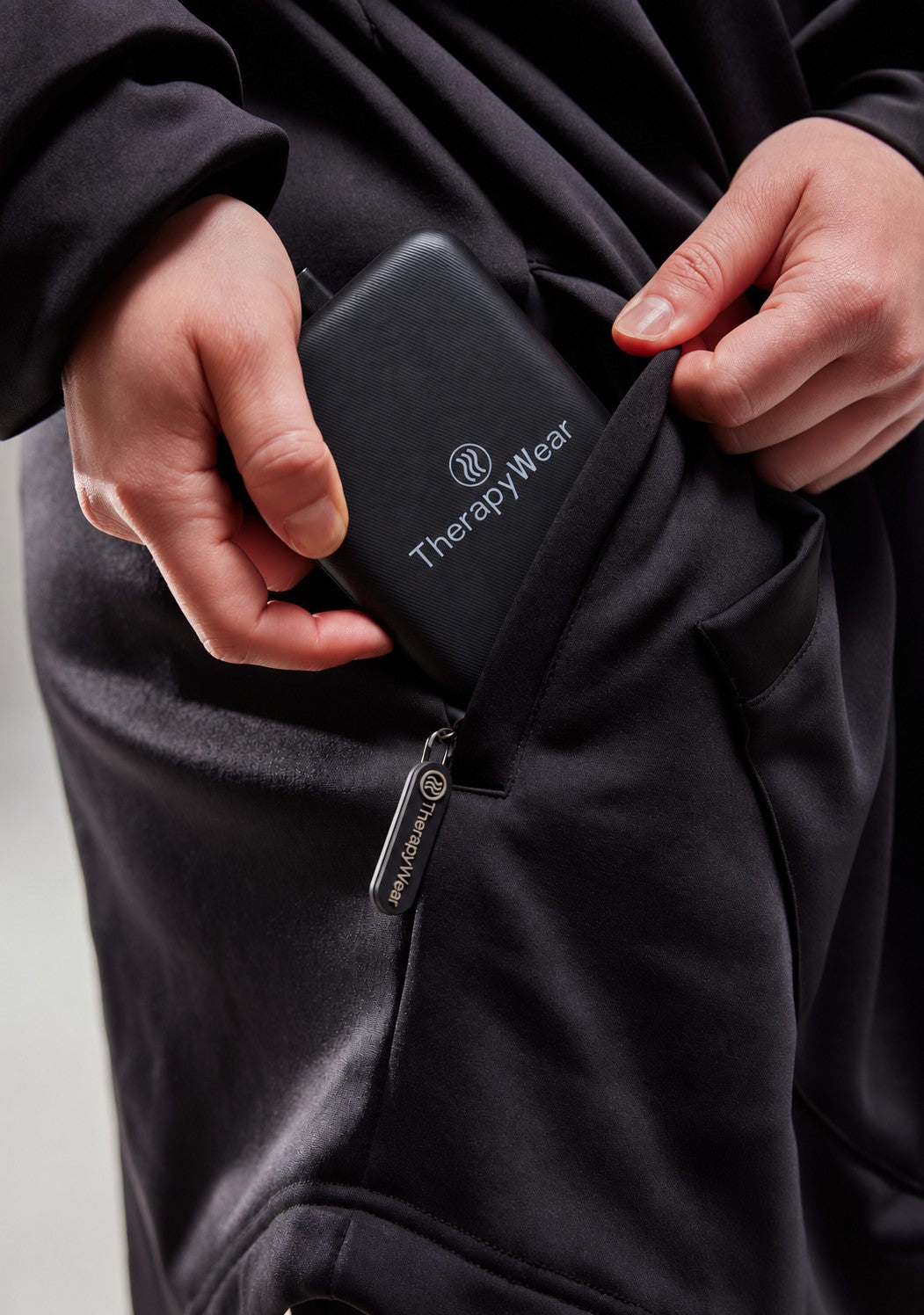 TherapyWear power bank going into the zipped pocket of the hoodie