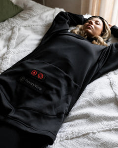 Woman relaxing on a bed in the TherapyWear Relief Hoodie