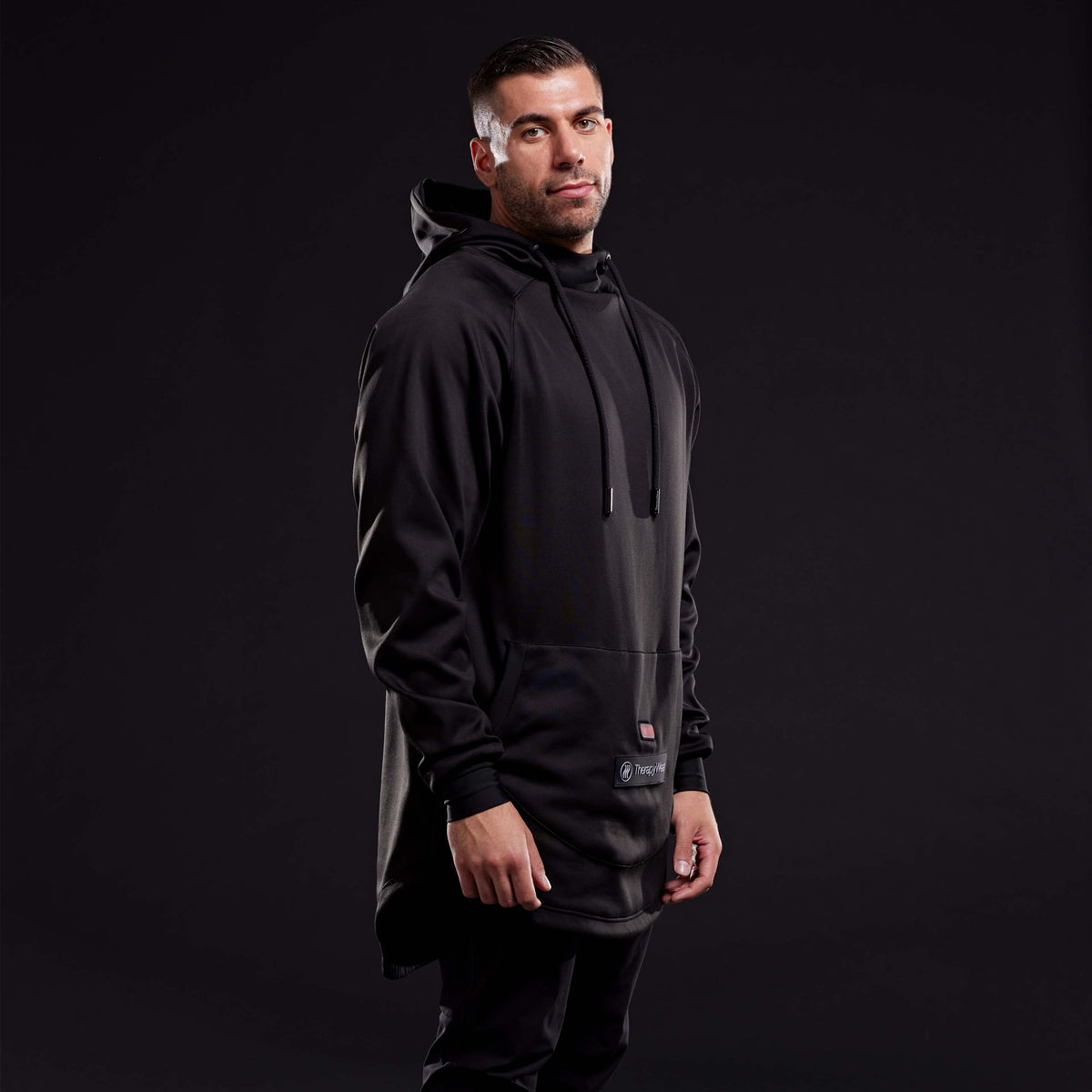 Man wearing the TherapyWear Relief Hoodie, side angle, in a dark studio